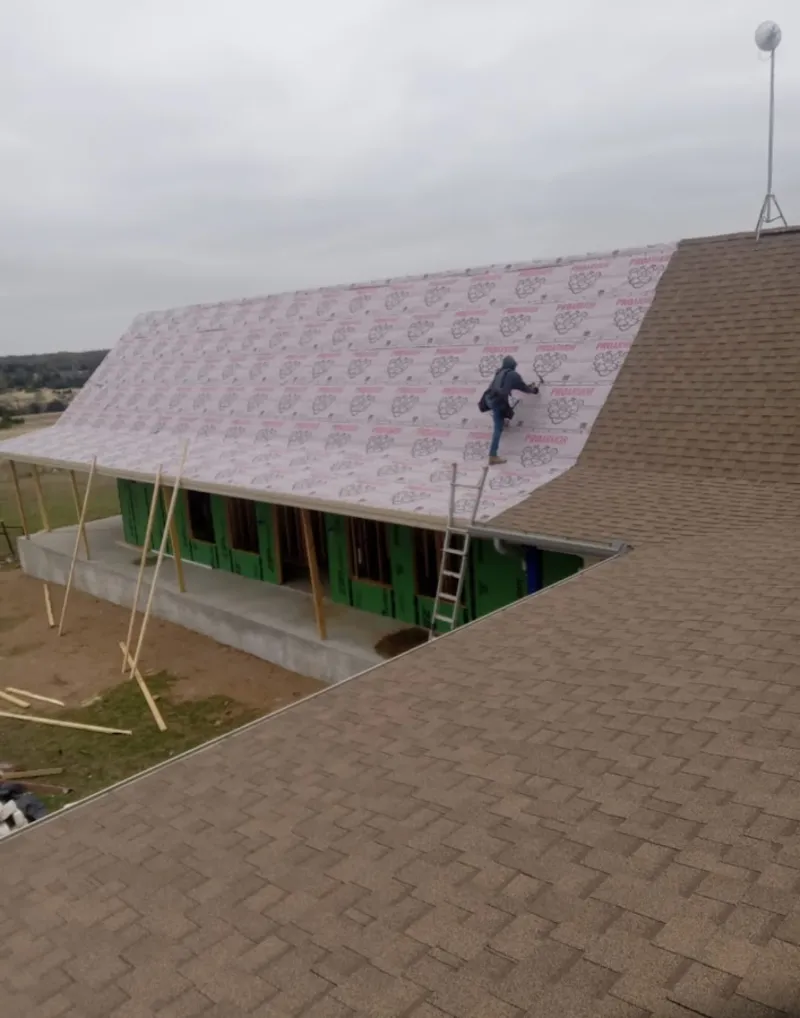 Worker preparing underlayment for a metal roof installation in Shelburne